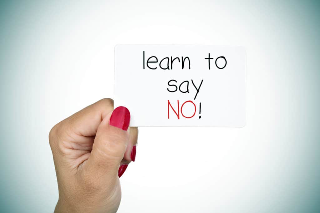 How to Set boundaries as a teacher - Why is it so important for educators to set boundaries? A ladies hand holding a little sign saying - 'Learn to Say No!'