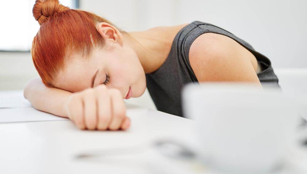 Teacher burnout quiz - teacher slumped over her desk in exhaustion